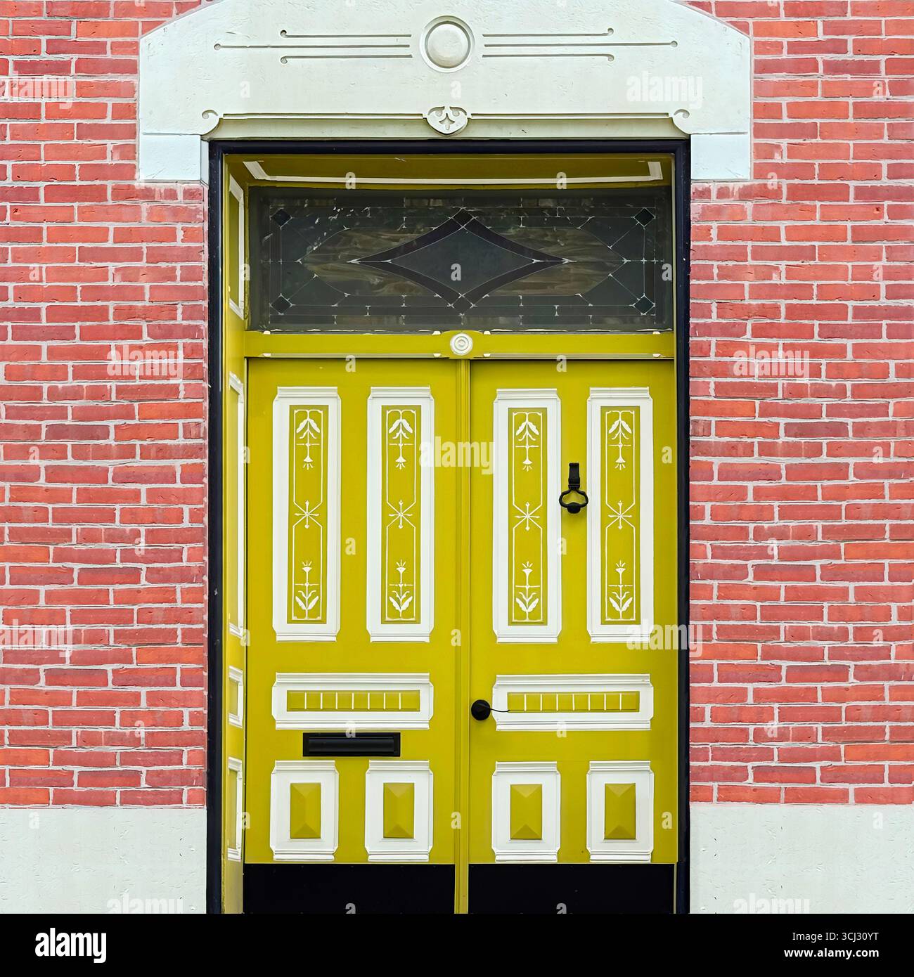 Ornate yellow double door with decorative panels framed by red brick facade in Chicago. - Smartphone Captured Stock Image