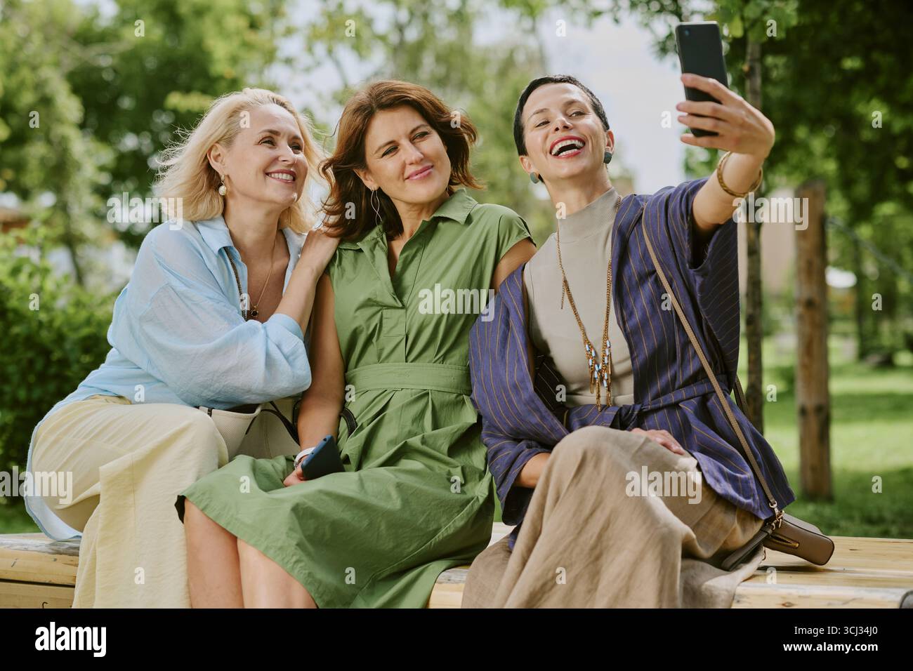 Three Middle Aged Women Smiling While Taking Selfie Outdoors Stock Photo