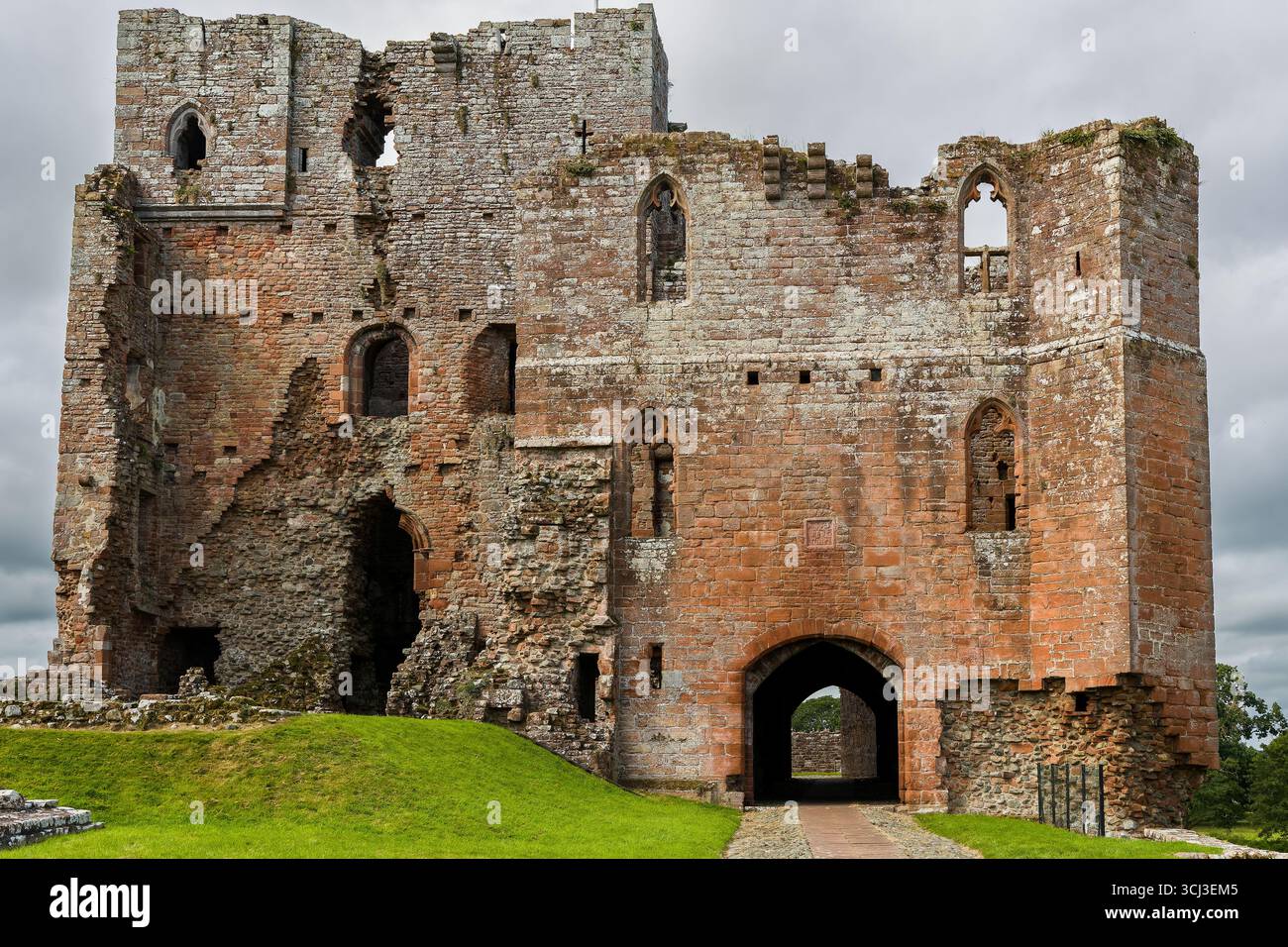 Historic red sandstone ruins of a medieval castle under an overcast sky ...