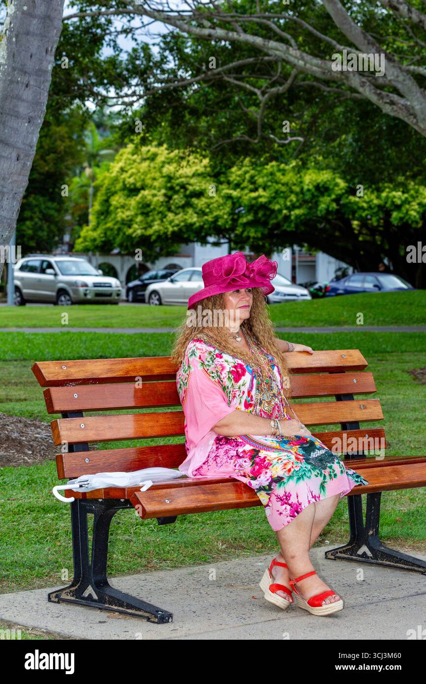 lady in pink admiring setting sun from park bench colour full dress long curly brown hair 50 plus models mature models modelling australia australian Stock Photo