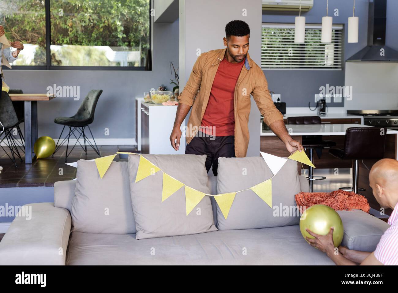 Man decorating living room with gold balloons and bunting for celebration Stock Photo