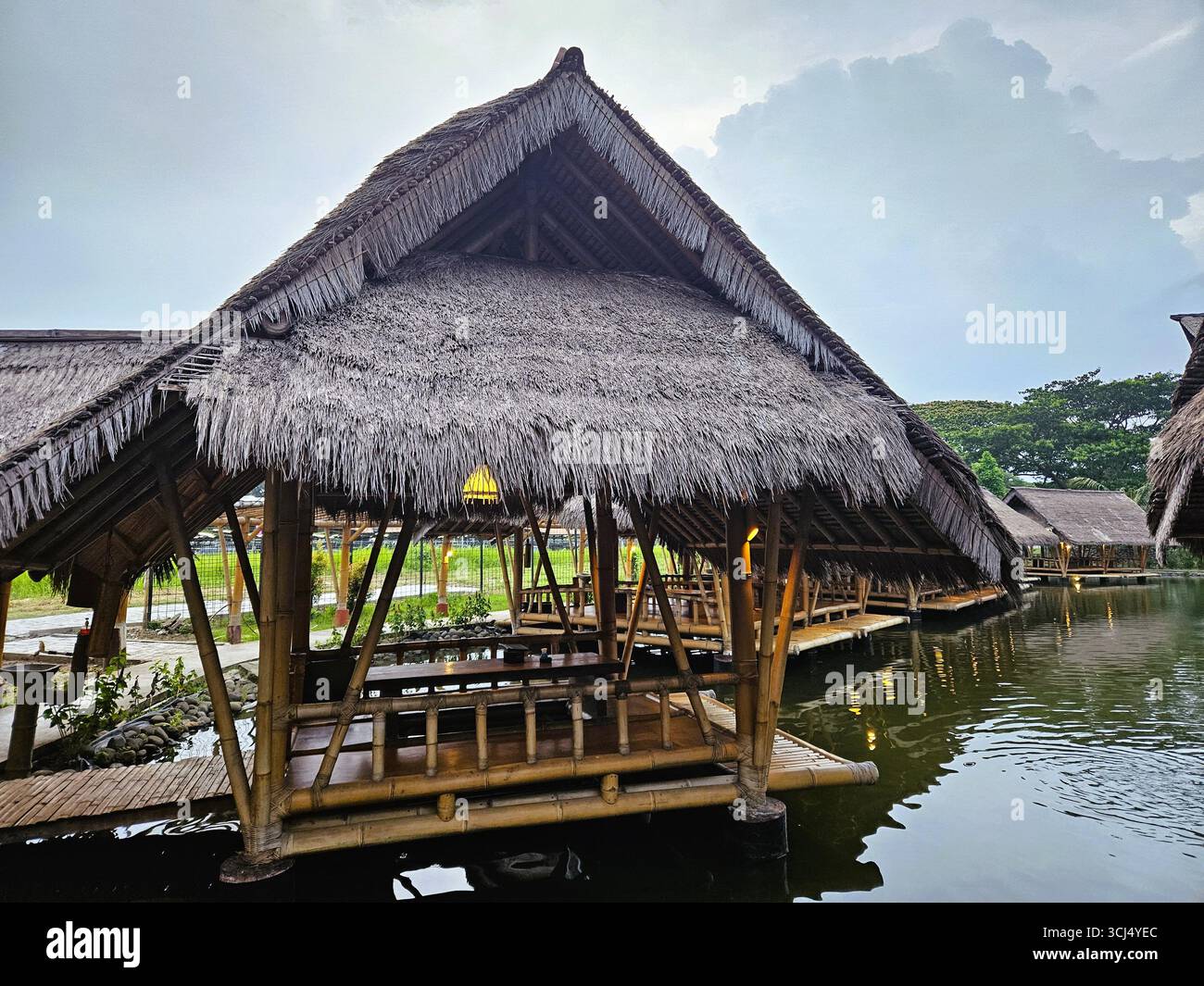 Traditional bamboo hut built on water pond in natural outdoor setting. Jakarta, Indonesia - March 3rd, 2024 - Smartphone Captured Stock Image