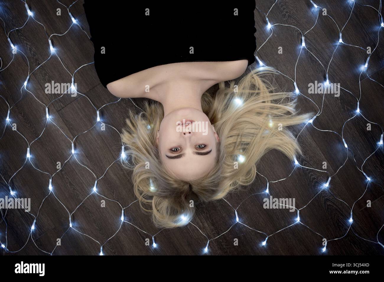 Beautiful girl lying on floor with christmas lights Stock Photo