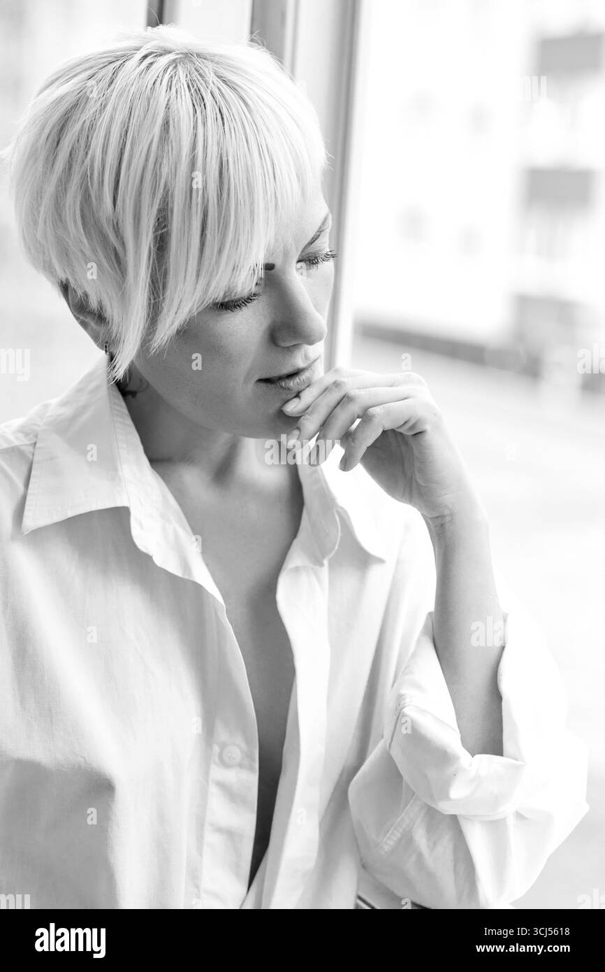 Sad woman thinker near window, monochrome Stock Photo