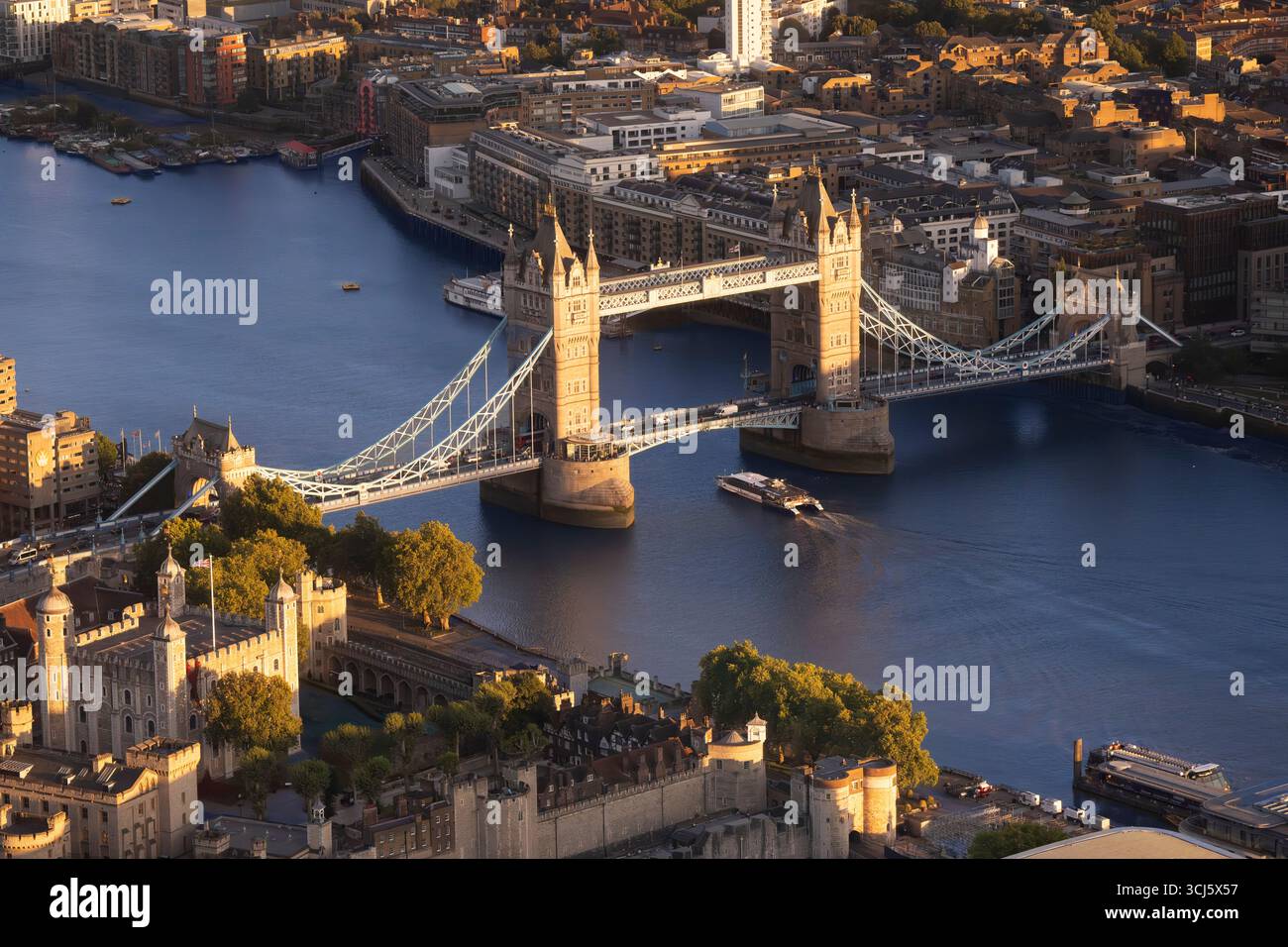 Tower Bridge, London. A boat travels on the Thames River near the Tower of London at sunset. Stock Photo