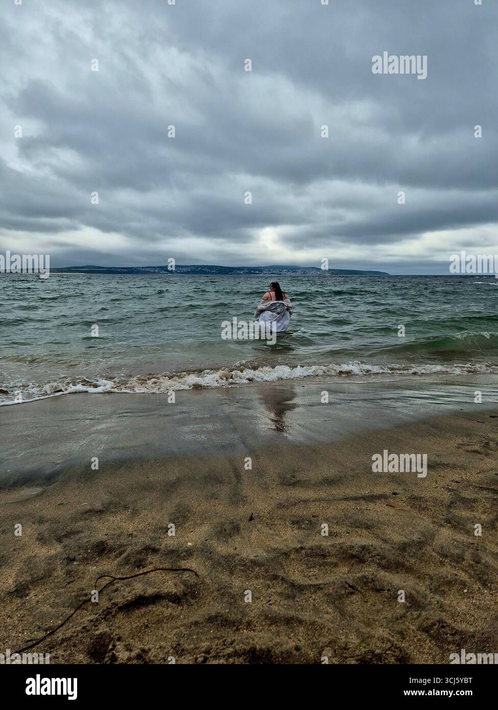 Lady in a whit shirt in a stormy sea in cornwall - Smartphone Captured Stock Image