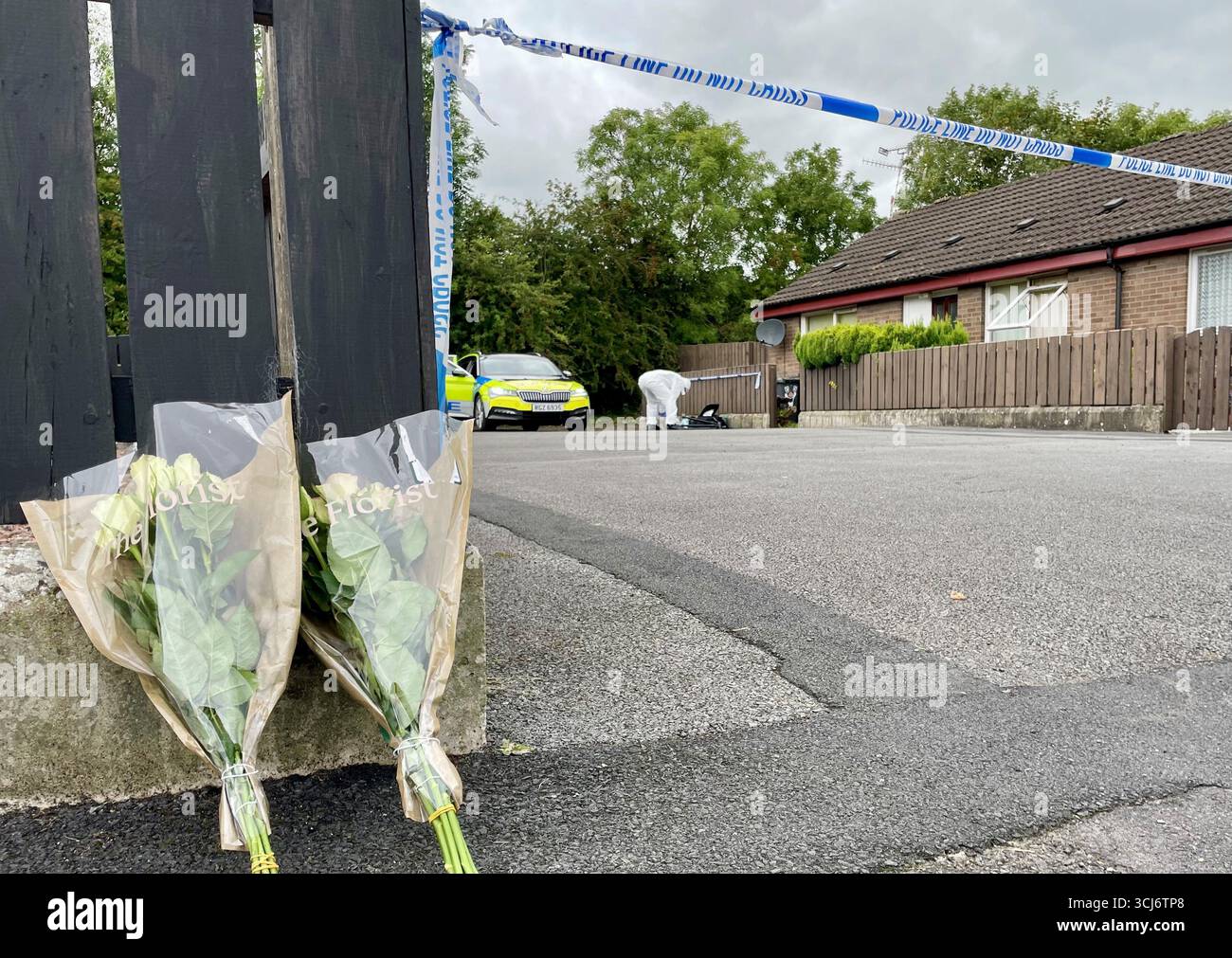 A general view of a floral tribute at the scene, in front of a police a