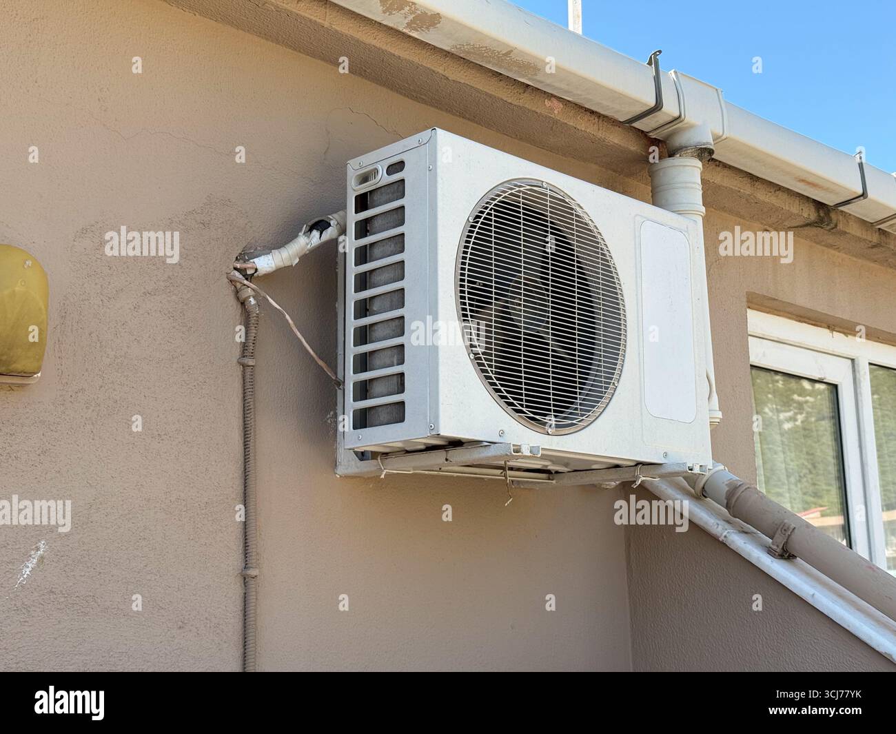 Air conditioning unit mounted on exterior building wall under clear ...