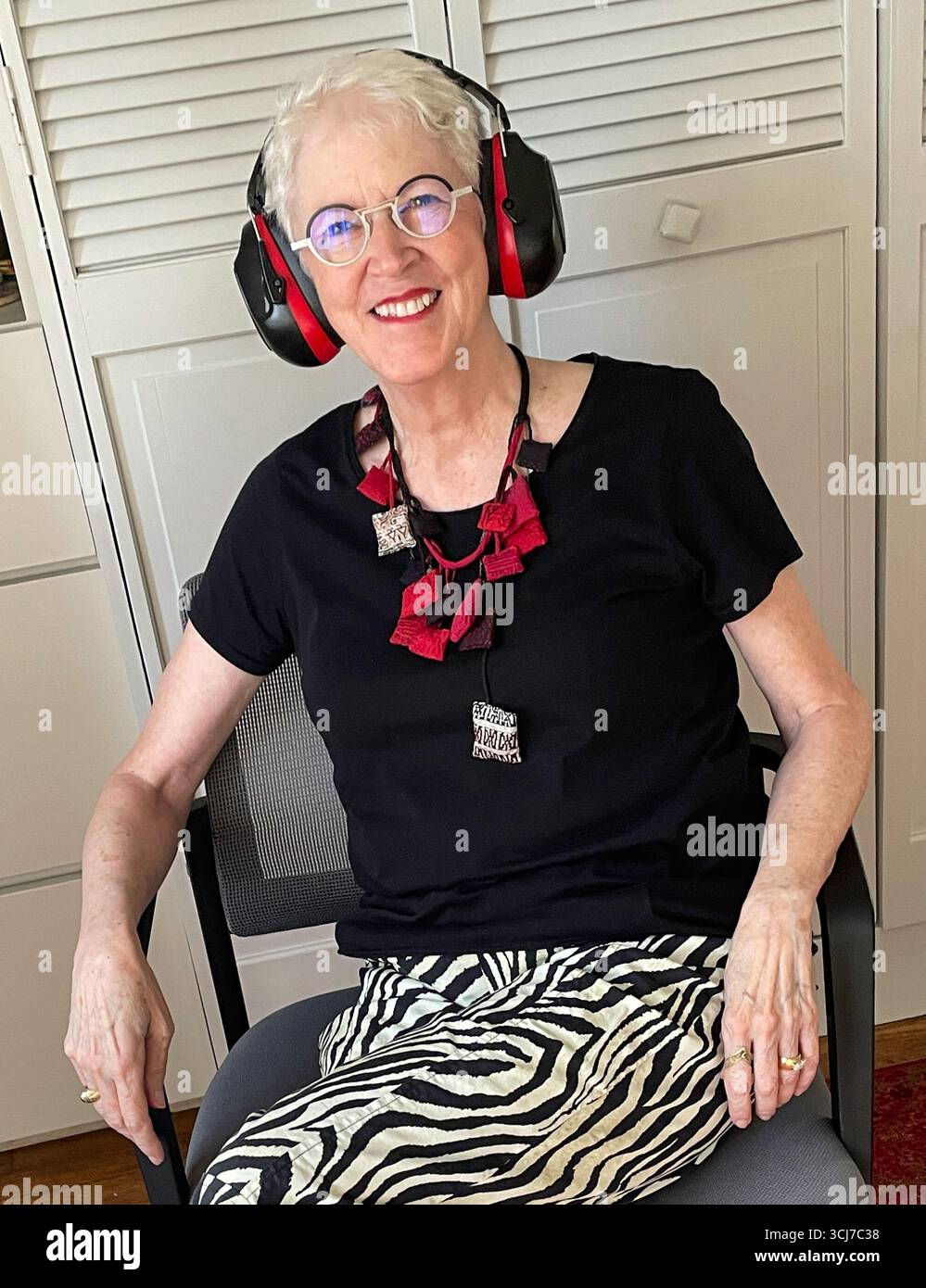 Portrait of a smiling, senior woman, fashionably dressed, wearing her matching noise canceling headphones, 2025, New York City, United States - Smartphone Captured Stock Image