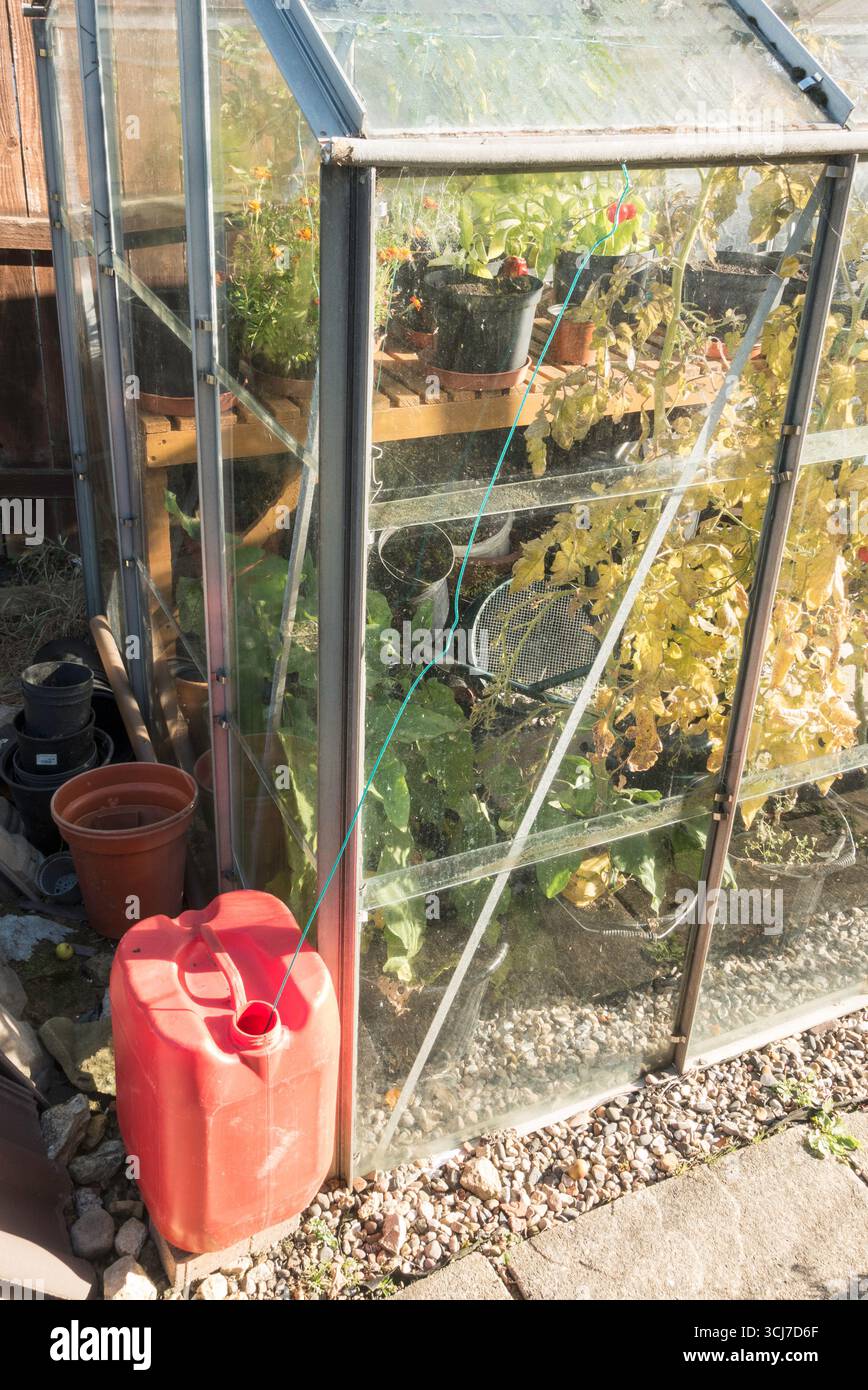 A Heath Robinson but effective method of collecting rainwater from an old  greenhouse using surface tension Stock Photo