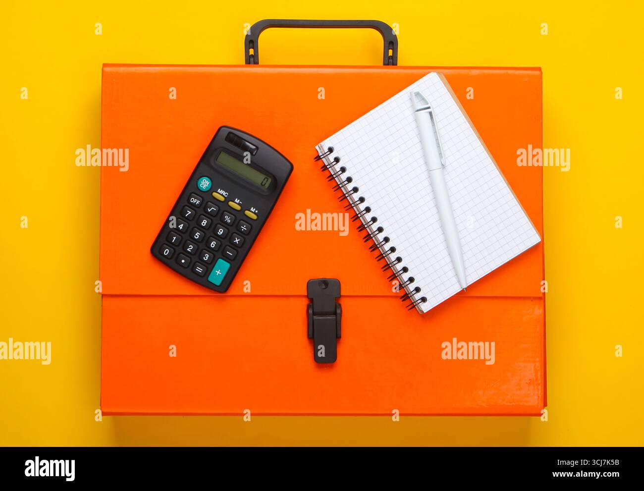 Orange paper case, notebook and calculator on a yellow background. Top view Stock Photo