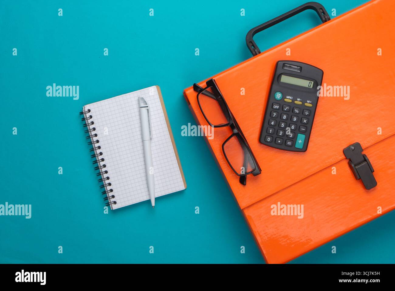 Orange paper case, notebook and calculator on a blue background. Top view Stock Photo