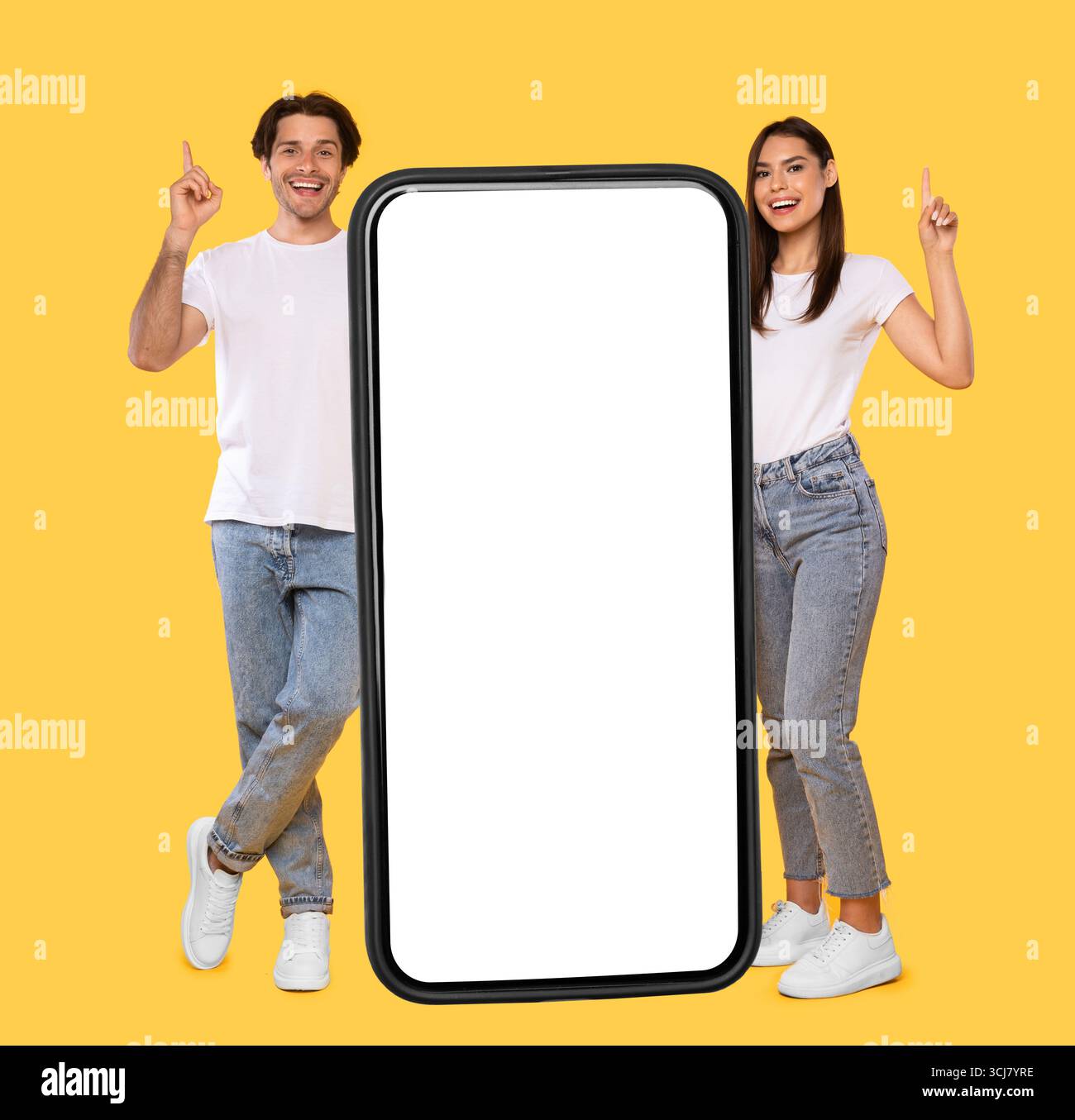 Couple standing next to big white empty smartphone screen Stock Photo