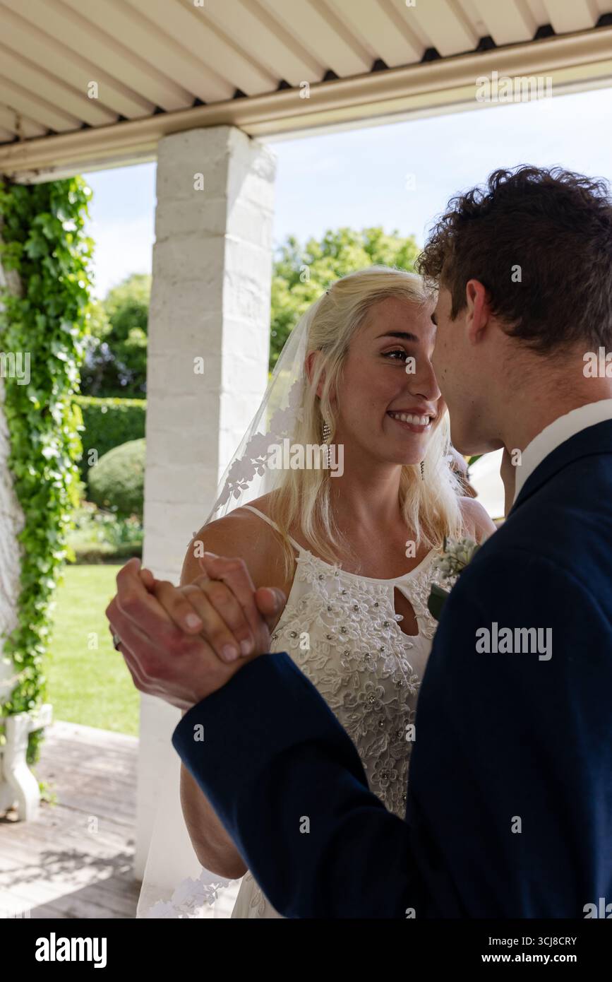 Bride and groom dancing joyfully under pergola, sharing loving moment Stock Photo