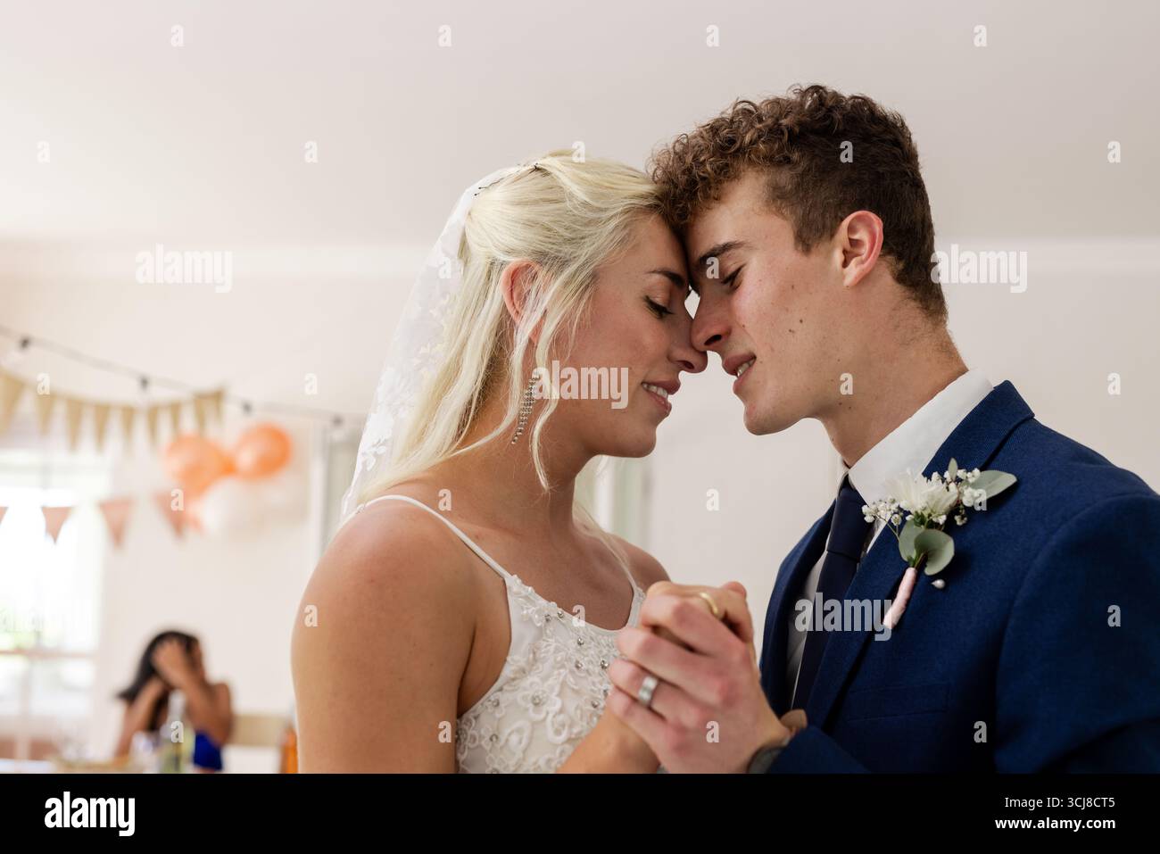 Bride and groom sharing intimate dance, smiling and holding hands at reception Stock Photo