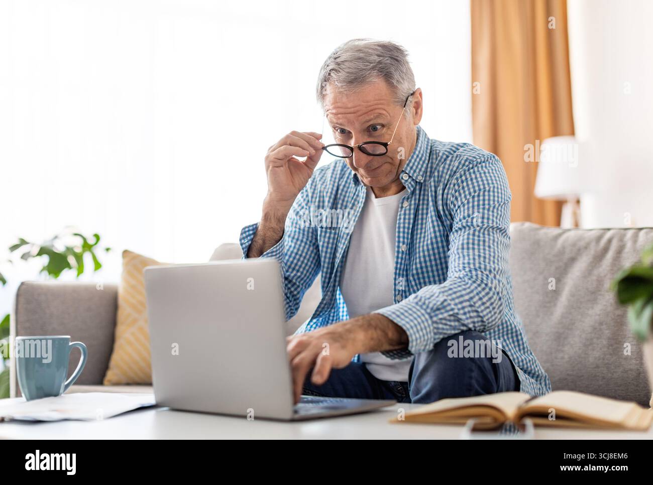 Surprised mature man using laptop looking at screen Stock Photo
