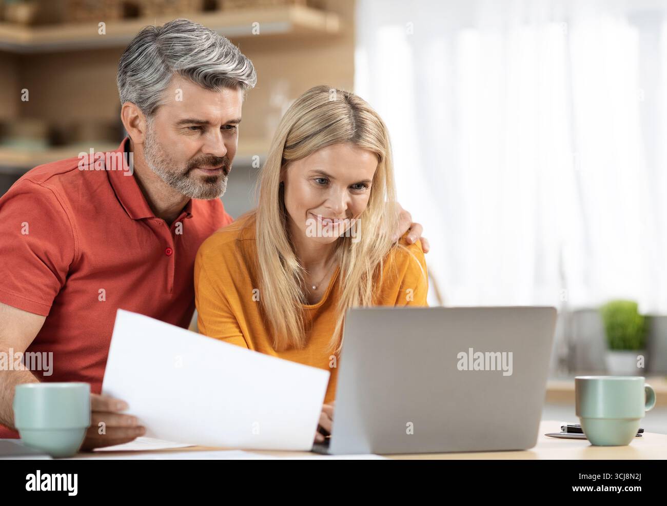 Attractive middle aged spouses working from home Stock Photo