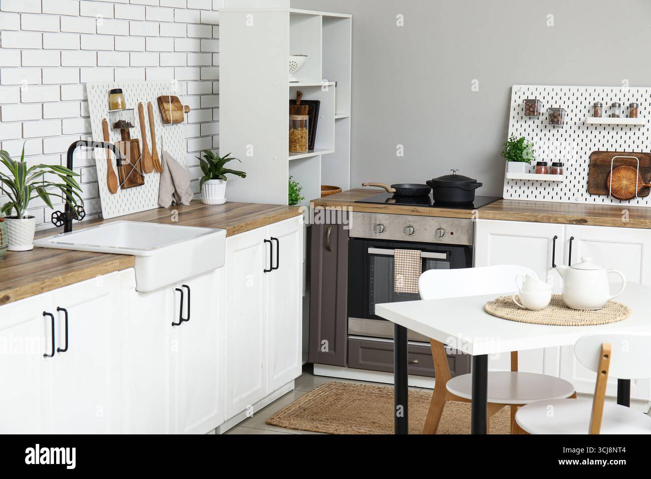 Stylish light kitchen with pegboards and modern dining table Stock Photo