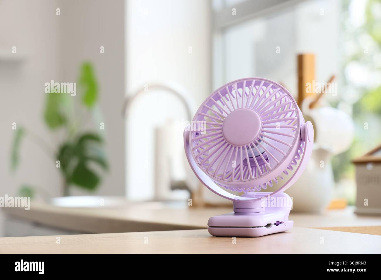 Lilac mini fan on table in kitchen, closeup Stock Photo