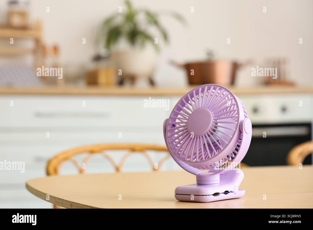 Lilac mini fan on table in kitchen, closeup Stock Photo