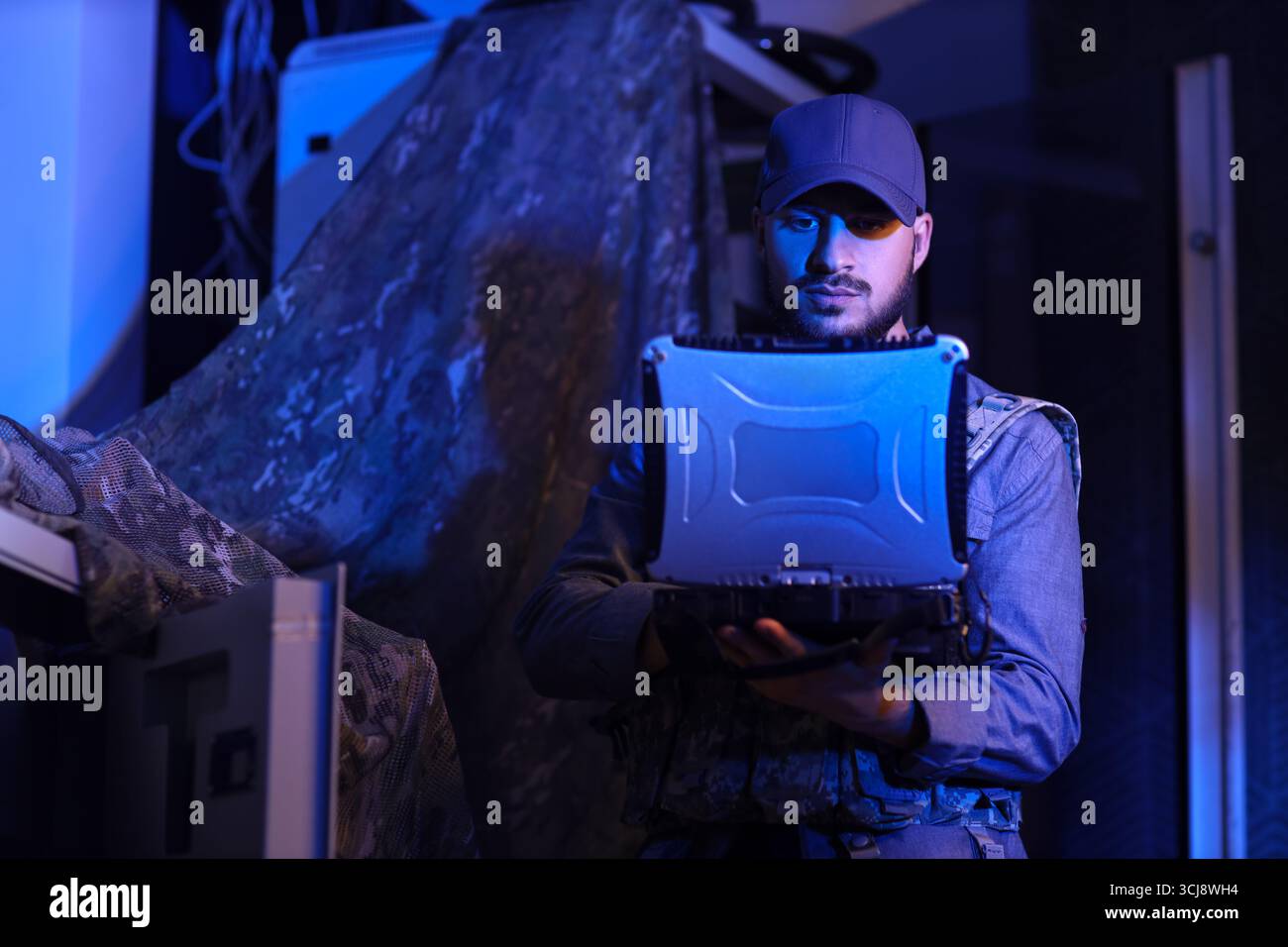 Young soldier working with military laptop in command center at night ...
