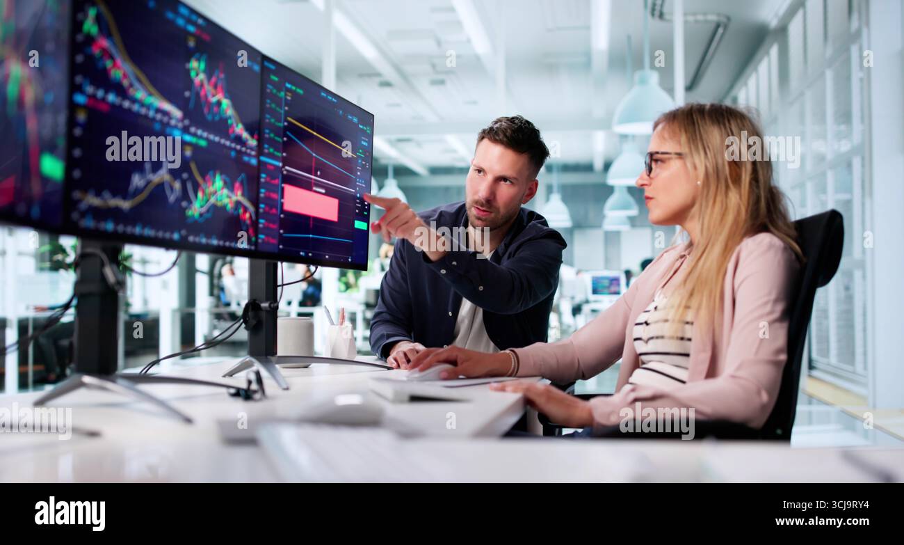 Financial Broker Analyzing Data On Multiple Computer Screens In Office Stock Photo