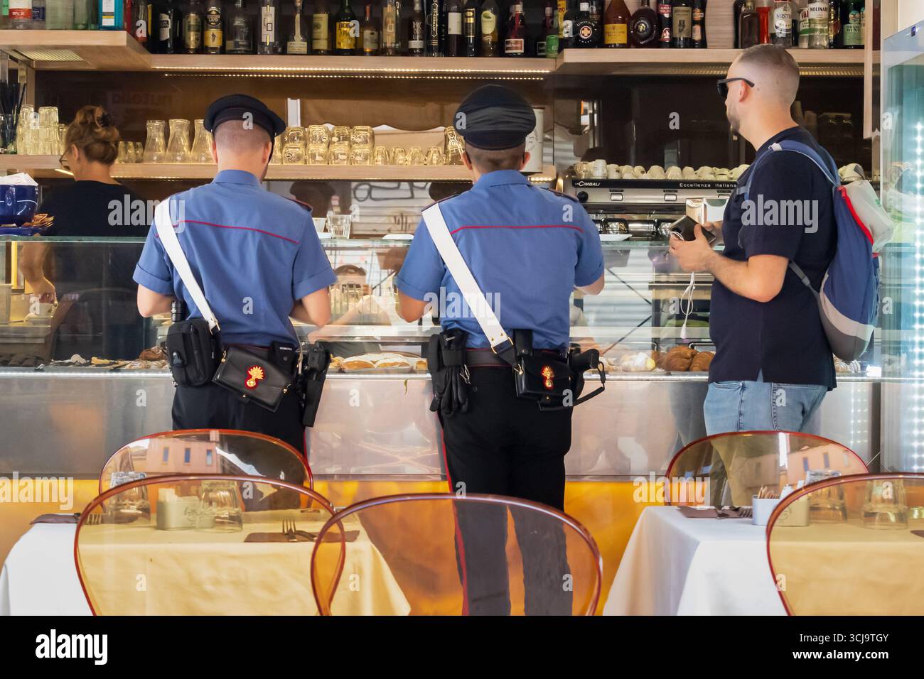 Two police officers and a tourist ordering coffee in a bar, Rome, Italy ...