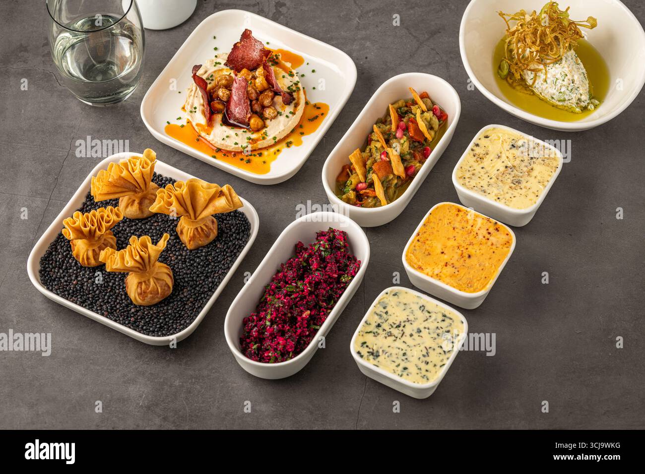 Assorted appetizers with dips, spreads, and vegetables on table Stock Photo