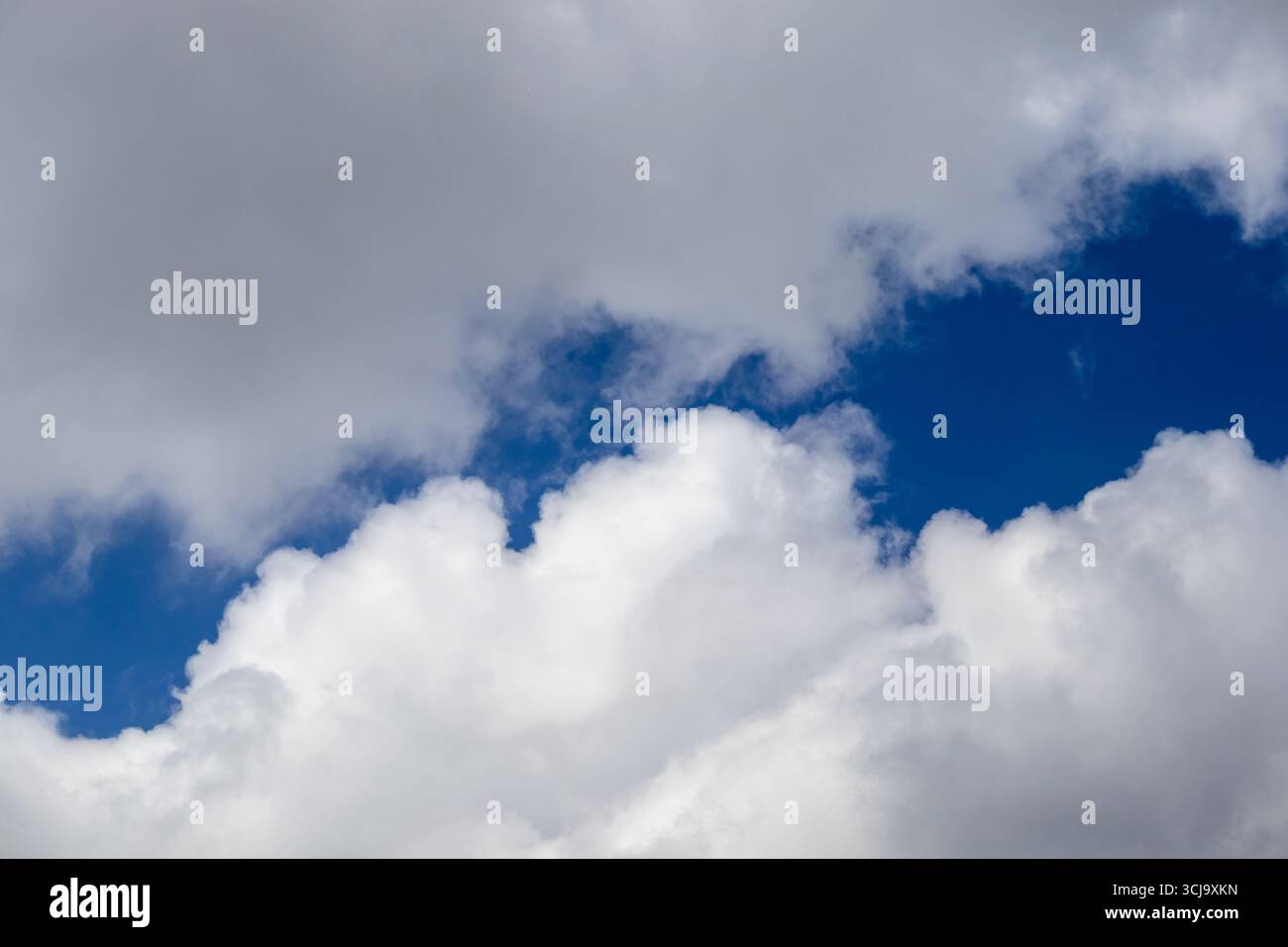 White cumulus clouds with patches of blue sky Stock Photo