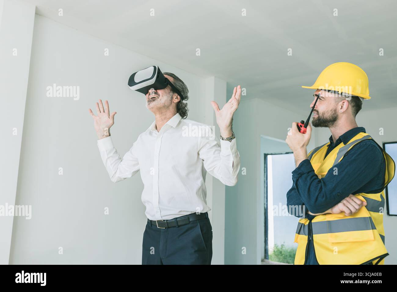 Construction manager happy exciting using VR visual reality presentation technology device present by builder at home contraction site Stock Photo
