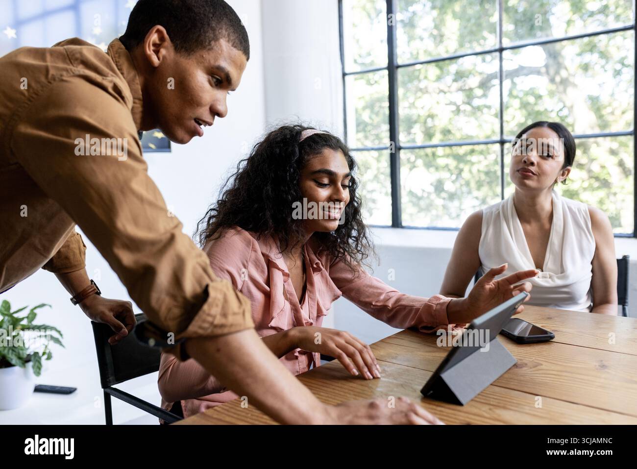Collaborating in modern office, team discussing project details using tablet Stock Photo