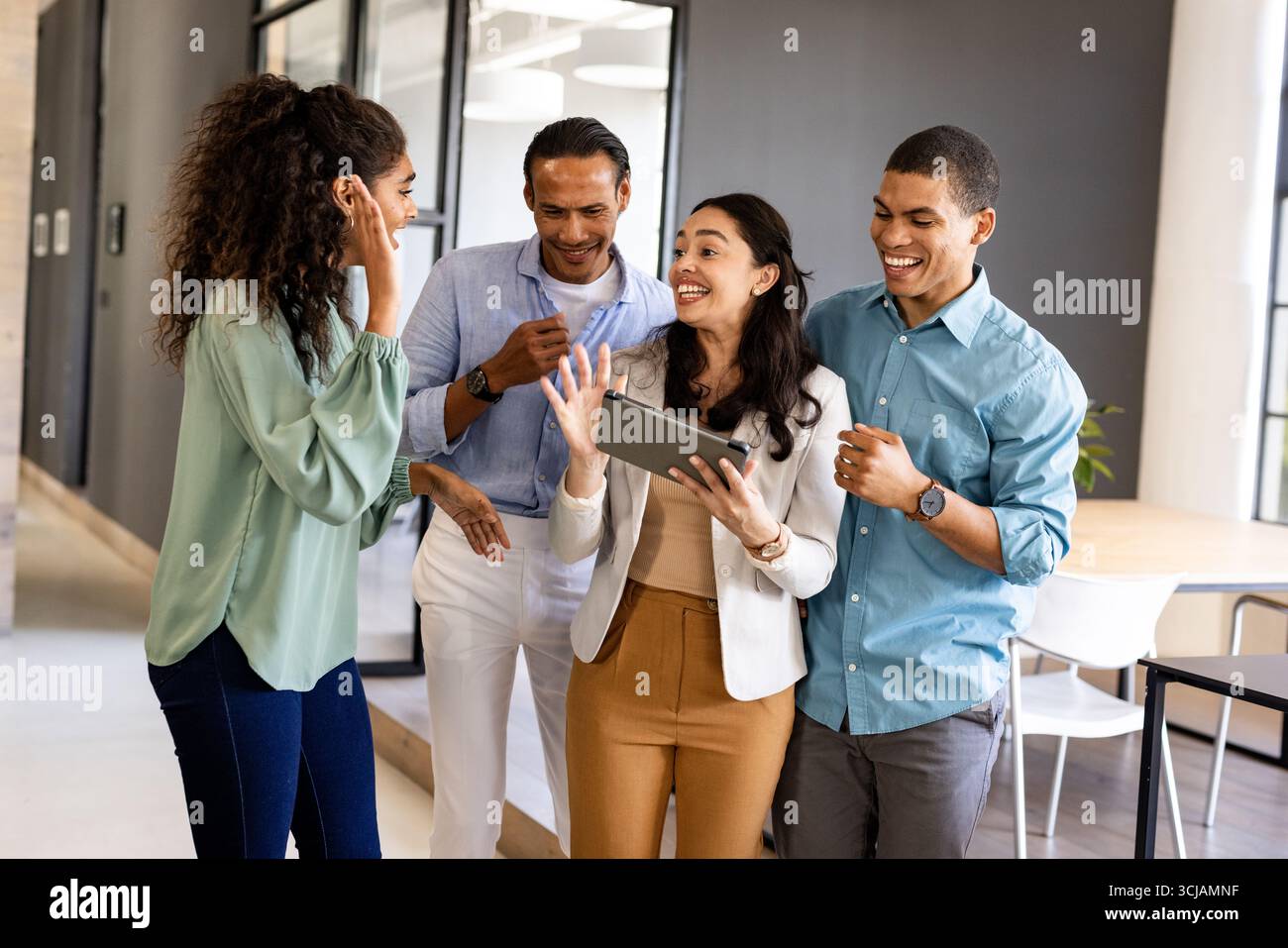 Business team collaborating and laughing while using tablet in modern office Stock Photo