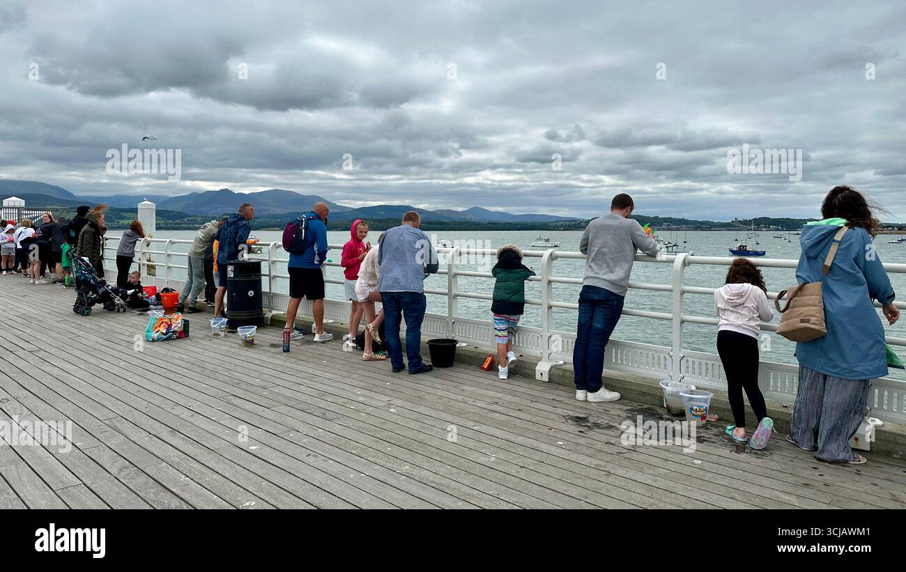 People fishing for crabs at Beaumaris Pier, Beaumaris, Anglesey, Wales - Smartphone Captured Stock Image