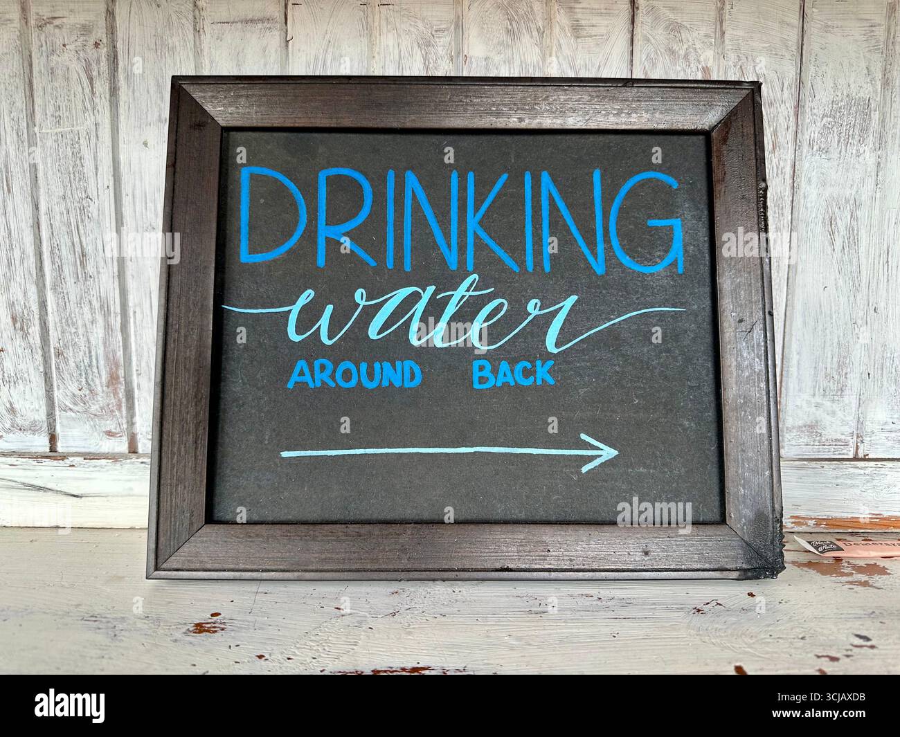 A sign giving directions for Drinking Water: Around back - Smartphone Captured Stock Image