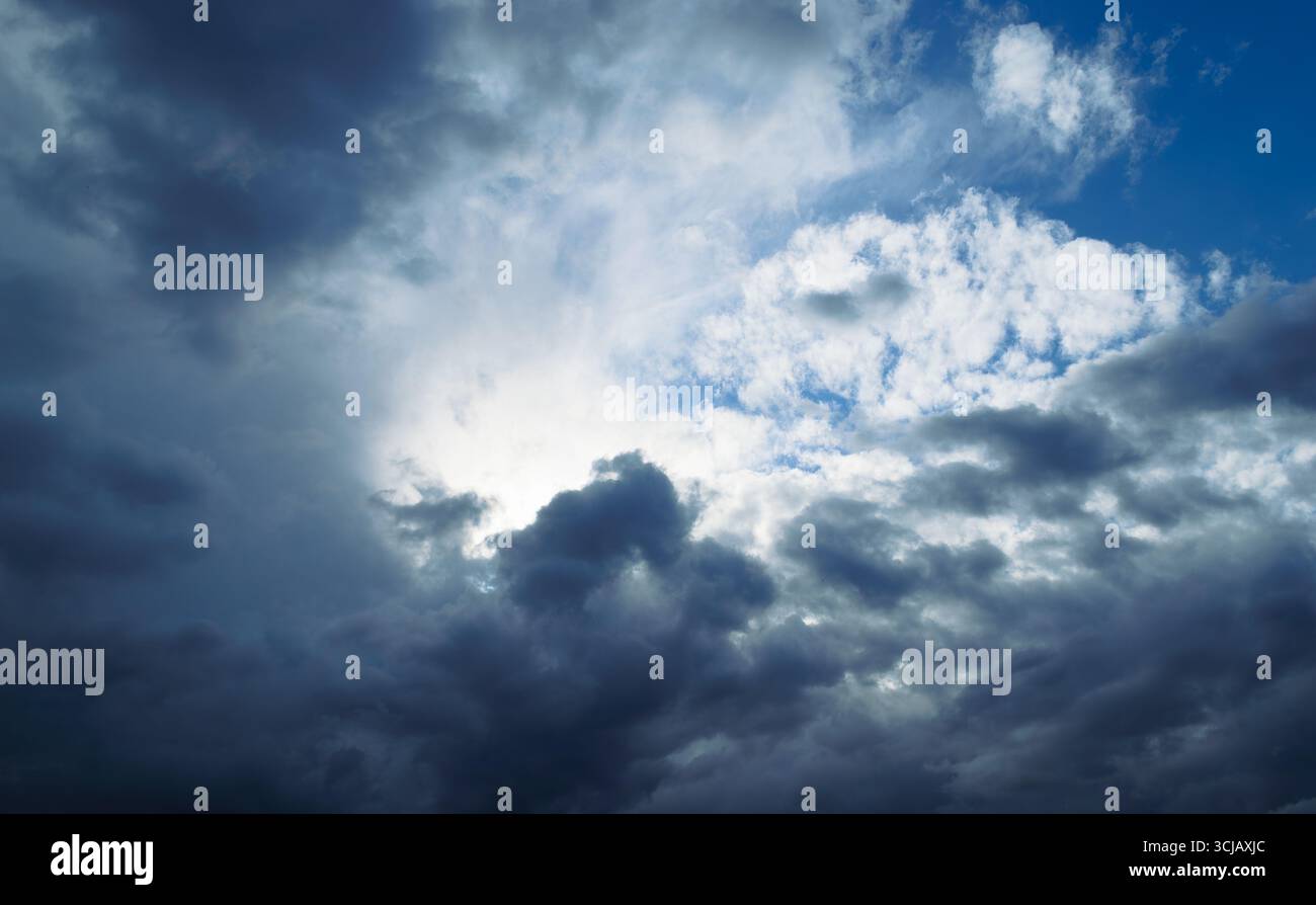 The sun is shining behind the rain cumulus clouds high in the sky Stock Photo
