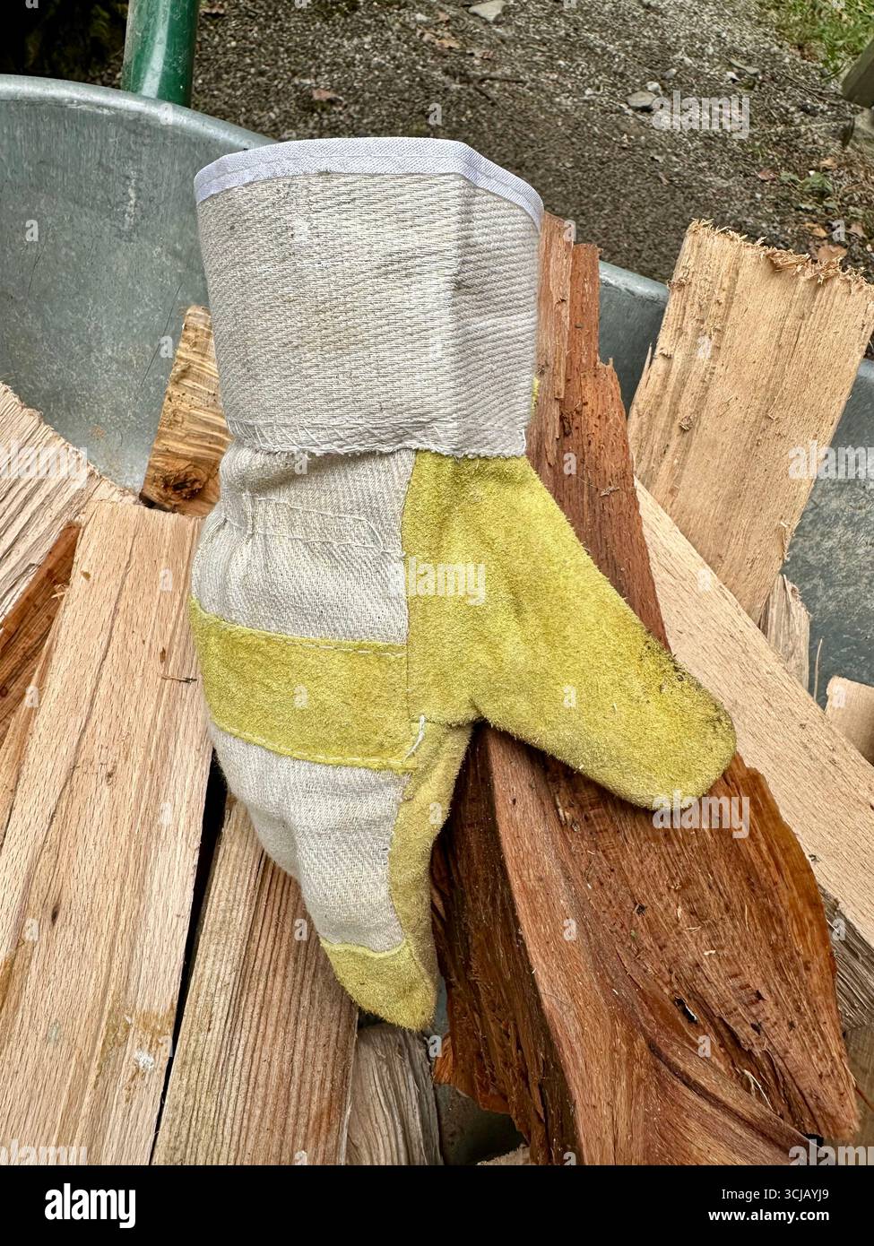 A work glove on a pile of logs in a wheelbarrow - Smartphone Captured Stock Image