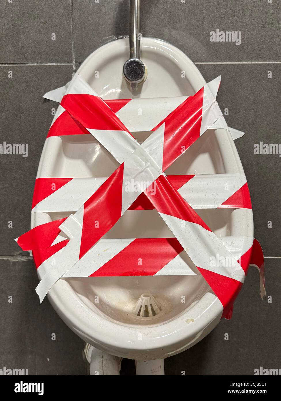 A toilet urinal with tape showing that the pumbing needs fixing or is out of use.  The cost to call out a plumber is an expensive business or domestic Stock Photo