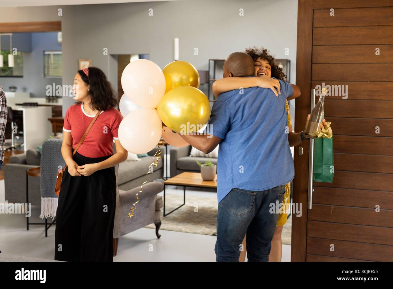 Hugging Balloons African American couple hugging with balloons and gift at home ...