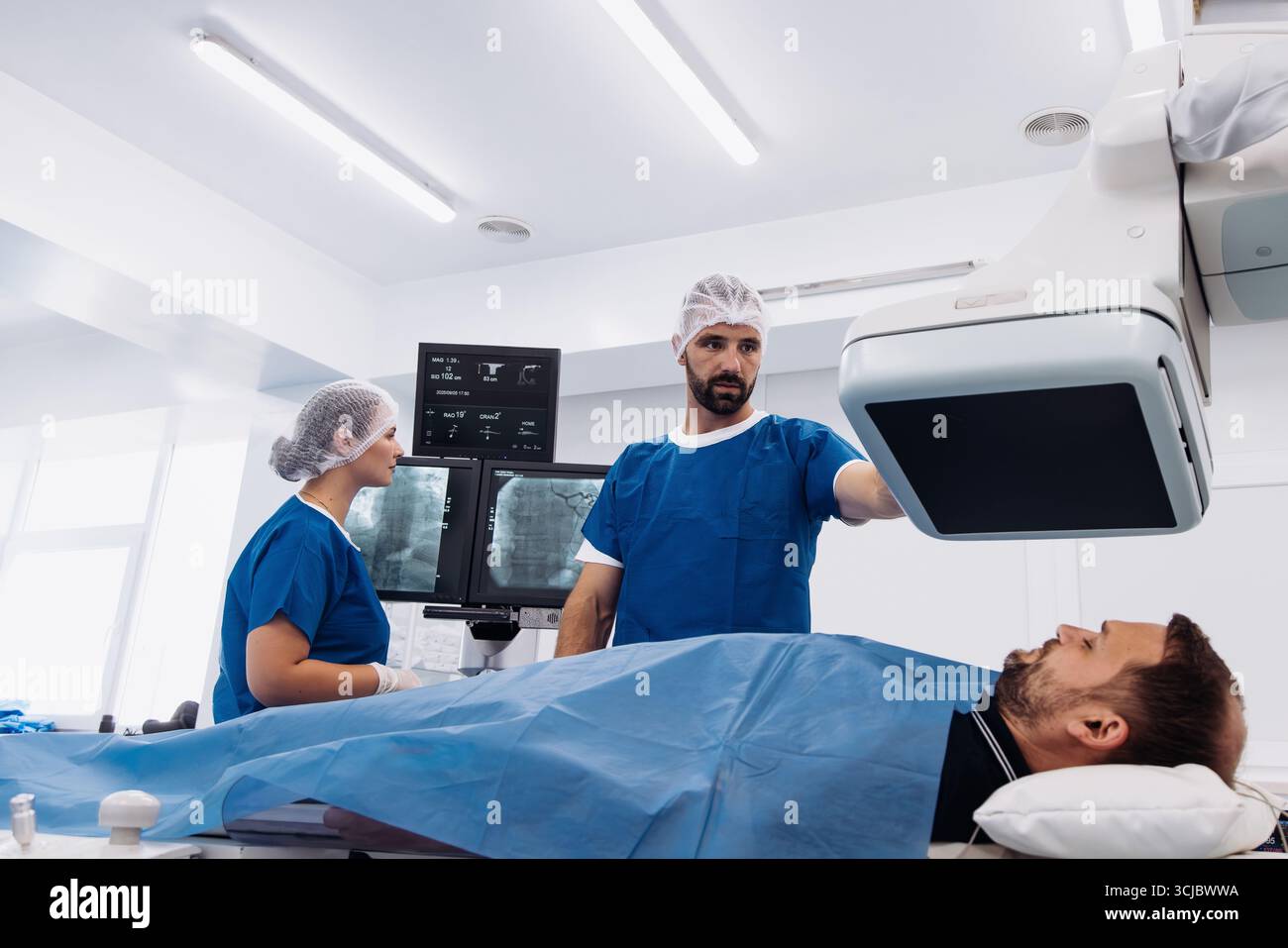 Medical professionals in blue scrubs are engaged in an angiograph ...
