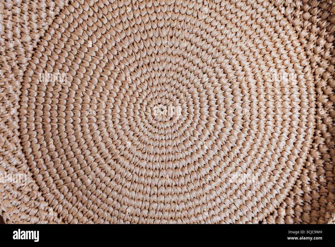 Circular weaving from natural brown raffia, close-up. Stock Photo