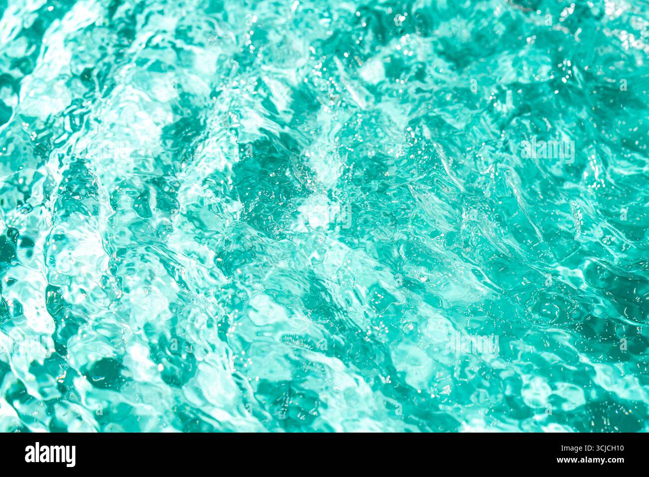 A close-up view of turquoise pool water, capturing the shimmering textures and dynamic patterns formed by sunlight reflecting off the rippled surface Stock Photo
