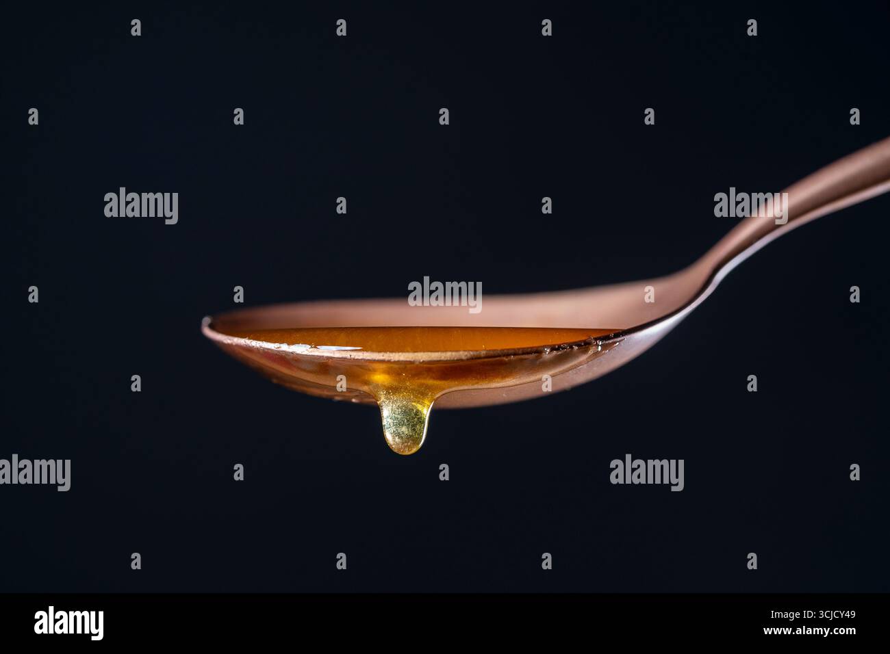 Spoon with honey. Thick honey dripping and flowing down from the one ...
