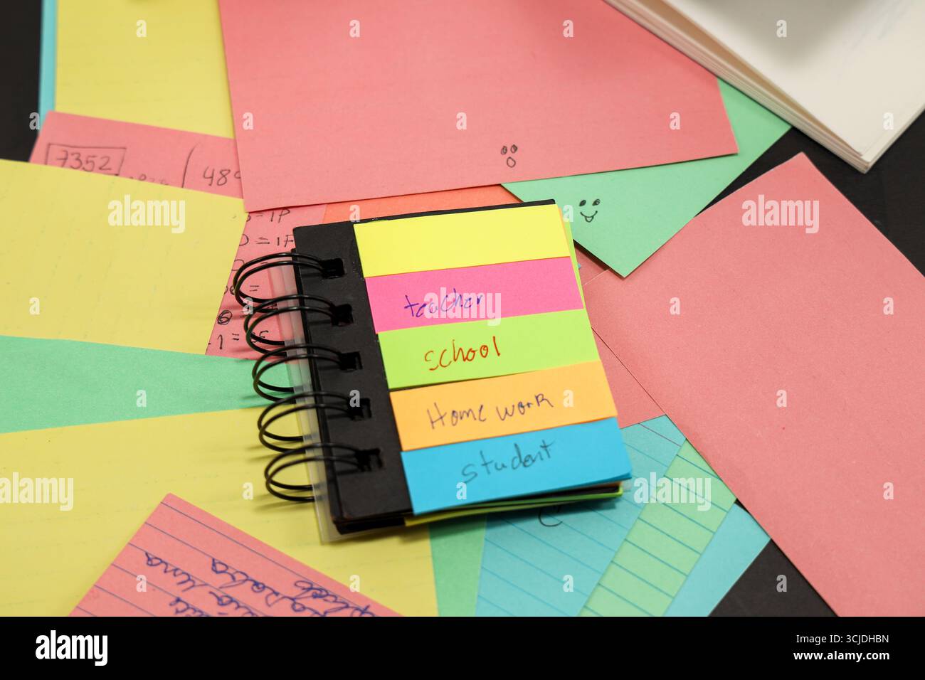 sticky notes with the words teacher, student, school, homework with more colored paper behind them Stock Photo