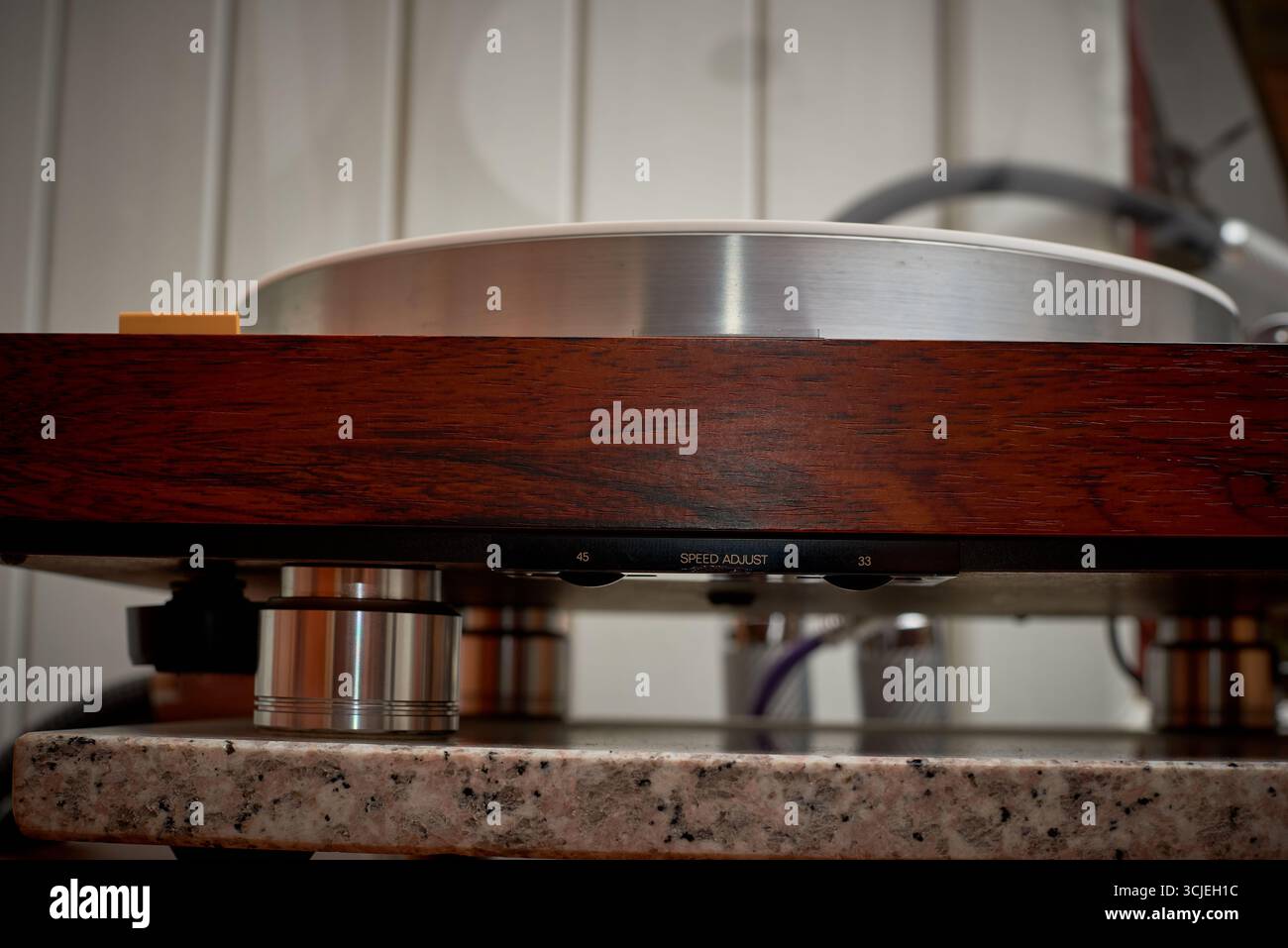 A classic turntable sits on a polished wooden surface, showcasing its smooth design and intricate controls. The warm, golden light enhances the cozy a Stock Photo