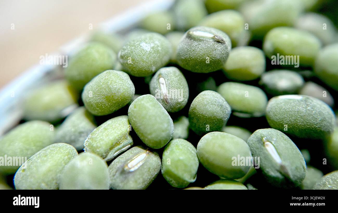 A close-up view of raw mung beans, showing their small oval shape, green color, and smooth texture, often used in cooking, sprouting, and healthy diet - Smartphone Captured Stock Image