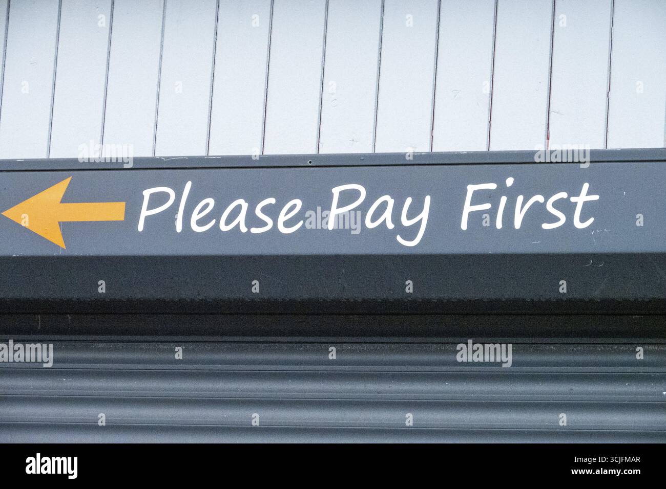 Pay First Note Sign with arrow pointing left and text please pay first indicating ...