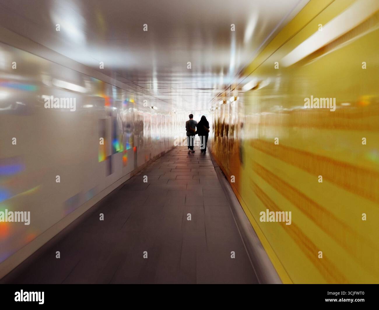 Pedestrian tunnel in Shoreditch, London. Two people in silhouette walking down tunnel with motion blur. - Smartphone Captured Stock Image