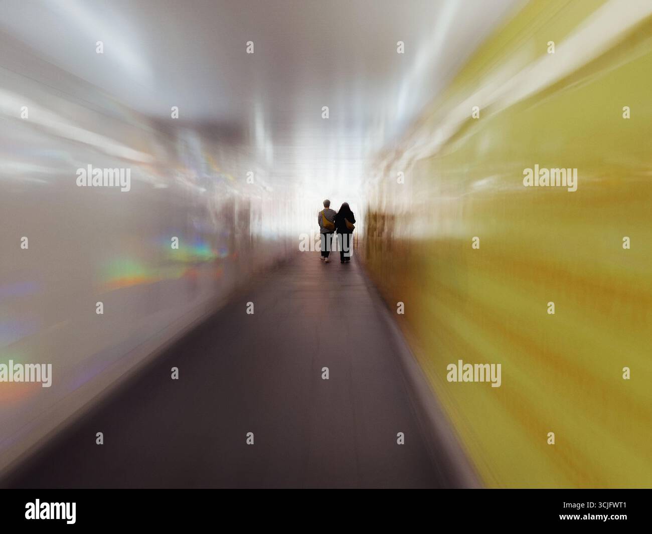 Pedestrian tunnel in Shoreditch, London. Two people in silhouette walking down tunnel with motion blur. - Smartphone Captured Stock Image