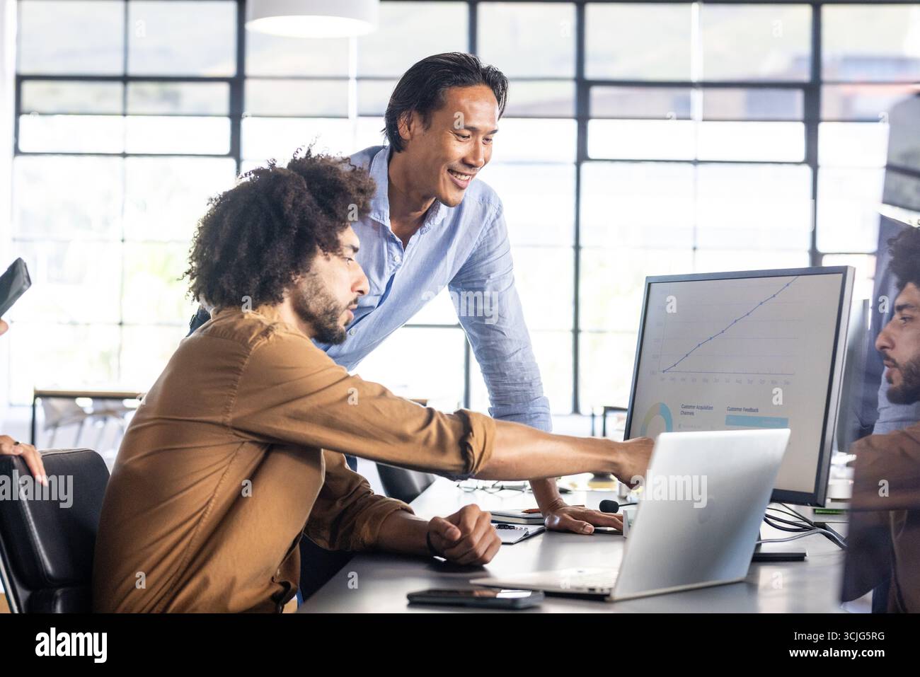 Analyzing data on computer screen, colleagues collaborating on project in office Stock Photo