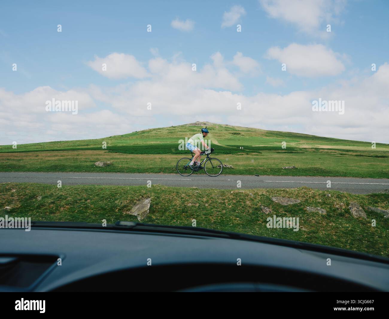 A lone cyclist passes by in the empty Dartmoor landscape Devon England UL Stock Photo